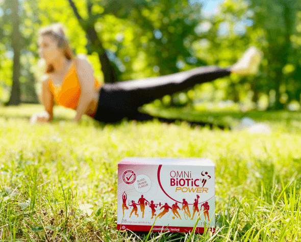 OMNi-BiOTiC® POWER na trawie a w tle ćwicząca osoba